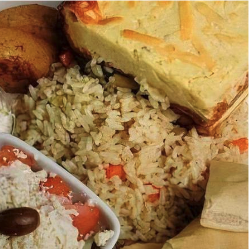 Moussaka at Dinakis Mediterranean Grill — Layers of potatoes, eggplant, zucchini, and hearty meat sauce topped with a rich bechamel sauce, served with rice pilaf, roasted potatoes, Greek salad, tzatziki dip, and pita bread.